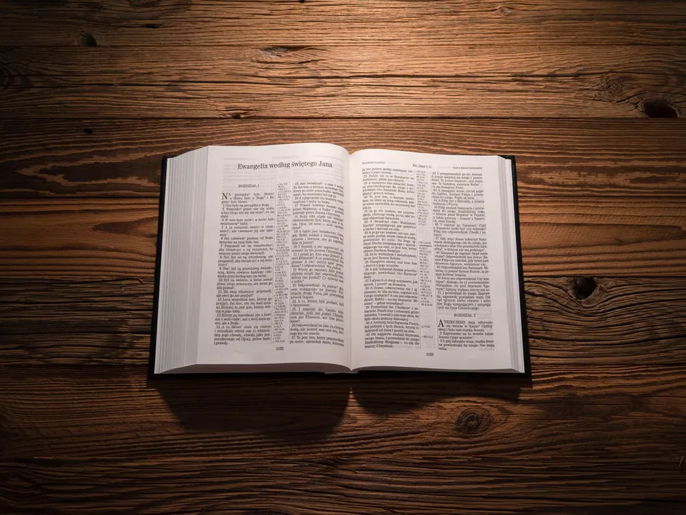 An open Bible on a wooden table, lit by warm evening light