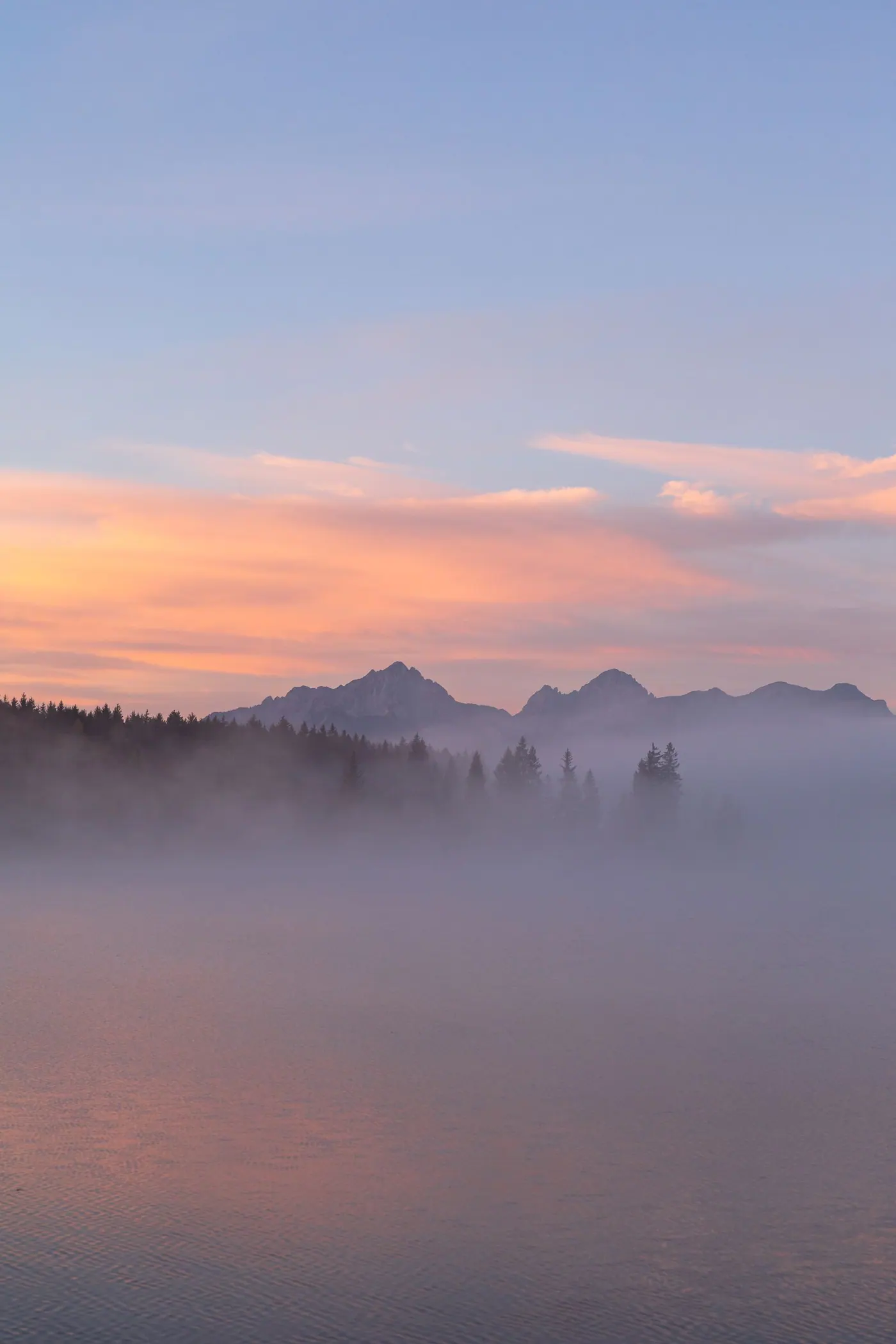 Misty mountain ridges under a pink sunset sky