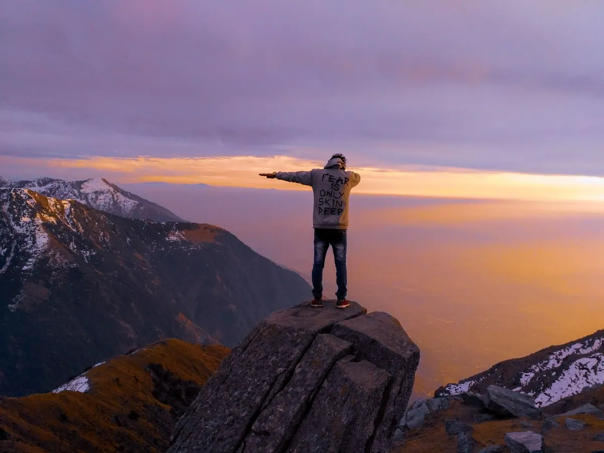 A hiker standing on a ridge at dawn with arms open